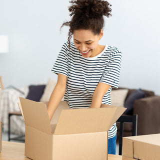 Person packing household items into plain cardboard boxes