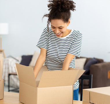 Person packing household items into plain cardboard boxes