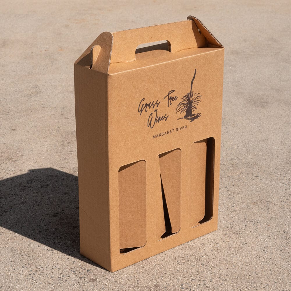 Brown cardboard wine gift box with 'GrasS Tree Wines' branding on a concrete surface.