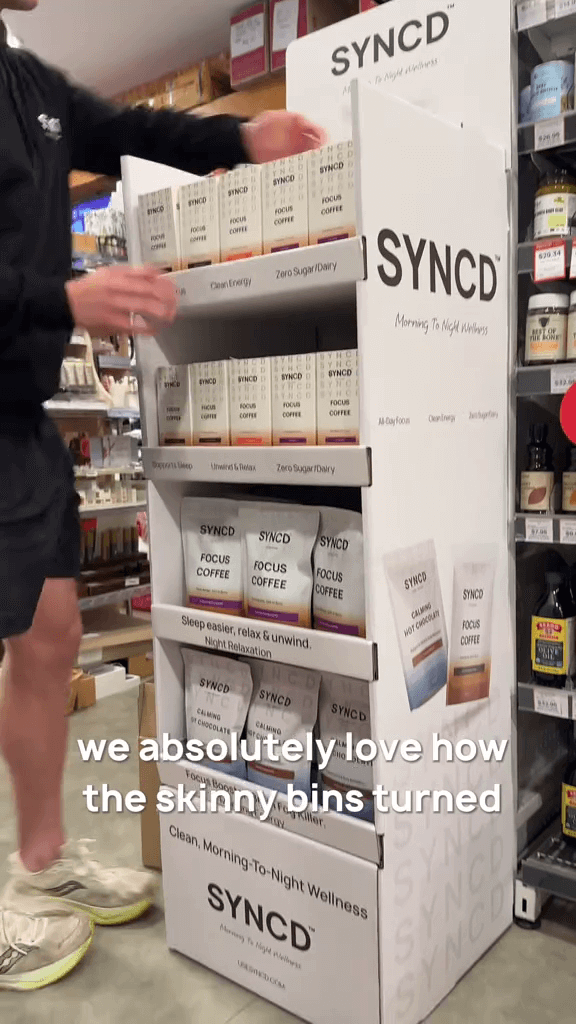 Display of SYNCD skinny bins in a store setting with a person interacting with it.