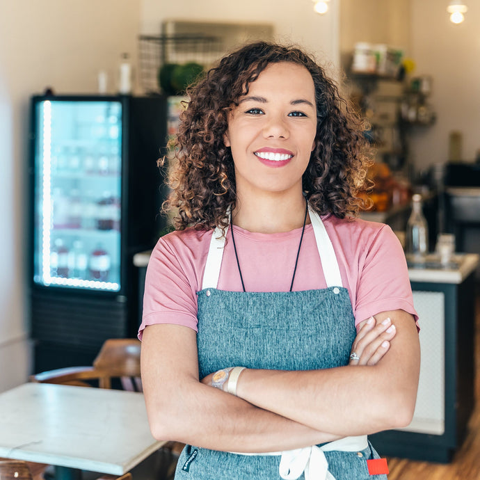 A Barista smiles proudly stood in her cafe