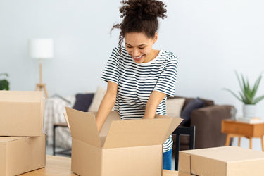 Woman unpacking cardboard boxes in a living room