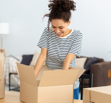 Woman unpacking cardboard boxes in a living room