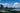City skyline with buildings and a body of water under a blue sky with clouds.